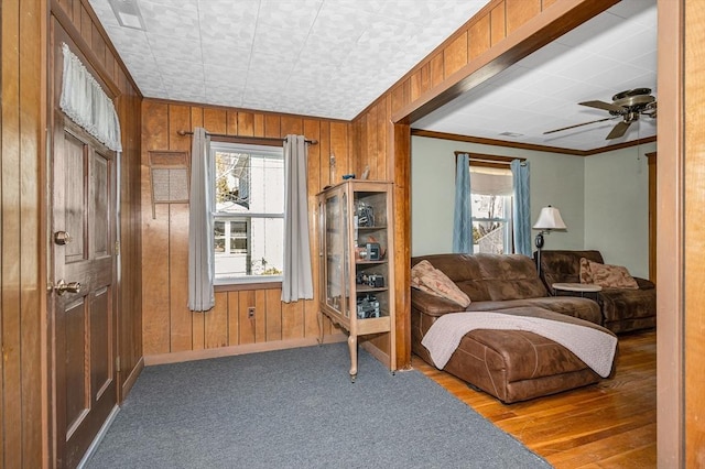 living area with wood walls, a wealth of natural light, and ornamental molding