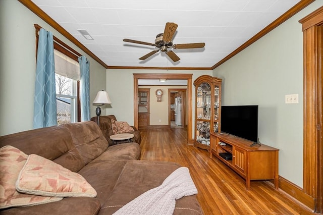 living area featuring crown molding, baseboards, light wood-type flooring, and ceiling fan