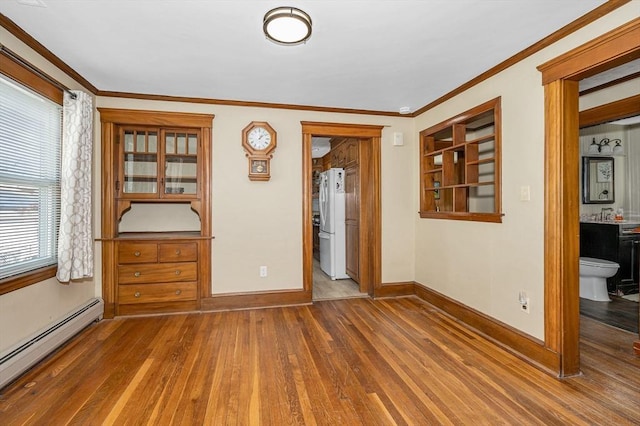 empty room with ornamental molding, a baseboard heating unit, baseboards, and wood finished floors