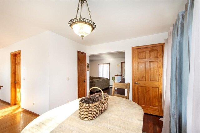 living room with plenty of natural light, a ceiling fan, a baseboard heating unit, and wood finished floors