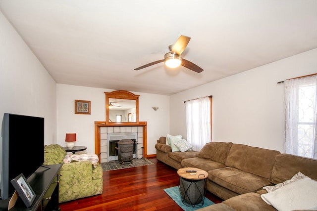 living room with a wealth of natural light, ceiling fan, a wood stove, and dark hardwood / wood-style flooring