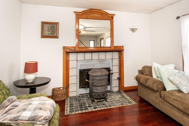 living area with a ceiling fan, baseboards, a tiled fireplace, and wood finished floors
