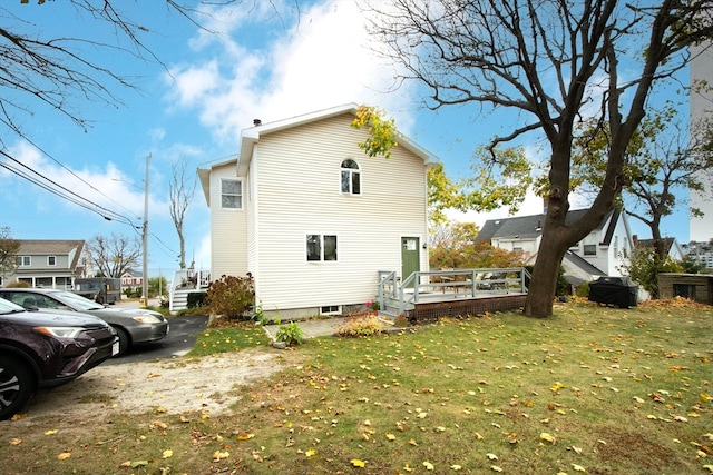 back of property with a wooden deck and a lawn