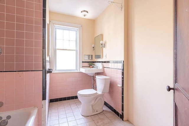 bathroom with tile patterned flooring, tile walls, sink, a bath, and toilet