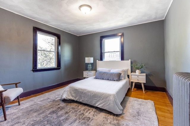 bedroom featuring hardwood / wood-style flooring, radiator, and crown molding