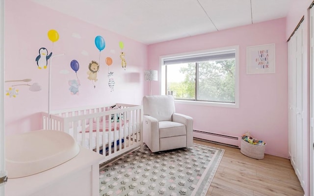 157 Franklin St Unit D3, Stoneham, MA 02180 - bedroom with baseboard heating, a crib, and light wood-style flooring