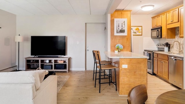 157 Franklin St Unit D3, Stoneham, MA 02180 - kitchen with appliances with stainless steel finishes, light wood-style flooring, a breakfast bar, light stone counters, and decorative backsplash