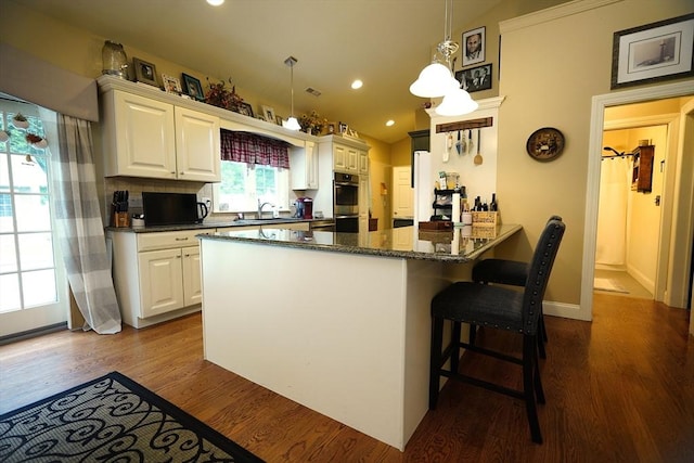 895 Dennison Dr, Southbridge, MA 01550 - kitchen with dark wood-style flooring, white cabinetry, stainless steel double oven, a peninsula, and recessed lighting