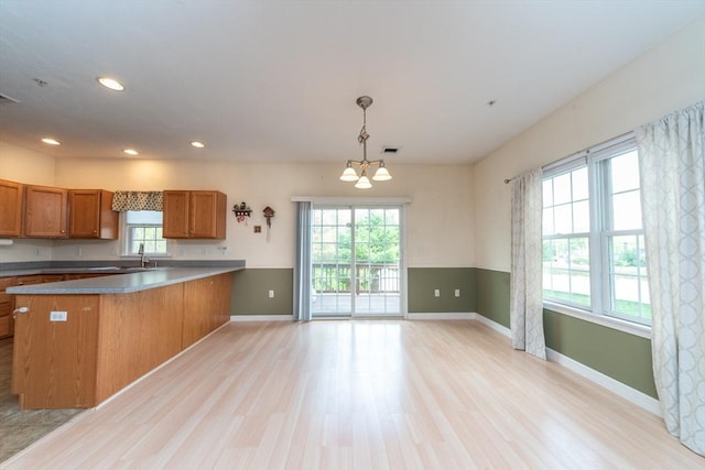 1 Knotts St Unit 1, Hudson, MA 01749 - kitchen with brown cabinets, light wood finished floors, a chandelier, baseboards, and a peninsula