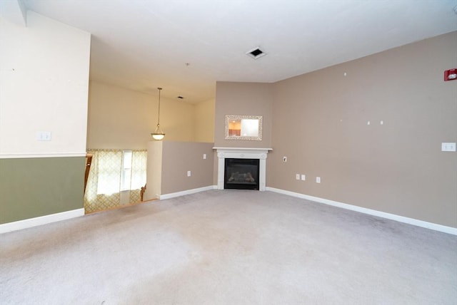 1 Knotts St Unit 1, Hudson, MA 01749 - unfurnished living room with baseboards, light carpet, a glass covered fireplace, and lofted ceiling