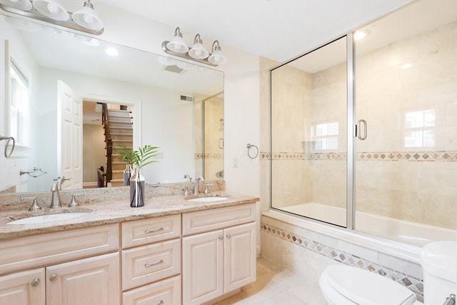 full bathroom featuring tile patterned flooring, dual vanity, toilet, and enclosed tub / shower combo