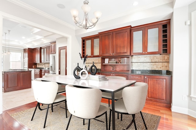 dining room with an inviting chandelier, sink, crown molding, light wood-type flooring, and a tray ceiling