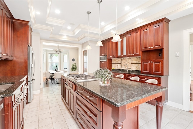 kitchen with decorative light fixtures, stainless steel appliances, a tray ceiling, decorative backsplash, and a kitchen island