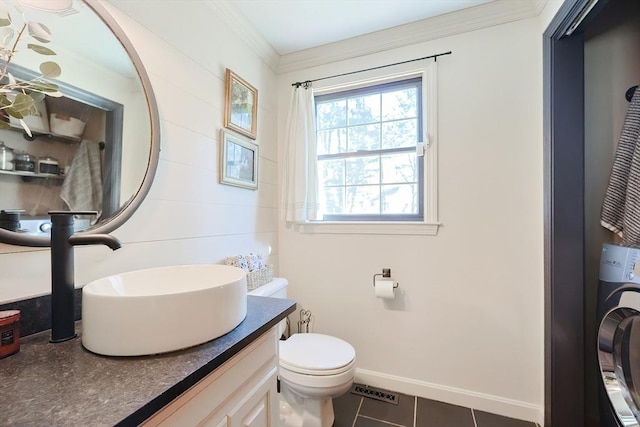 bathroom featuring toilet, washer / clothes dryer, crown molding, baseboards, and vanity