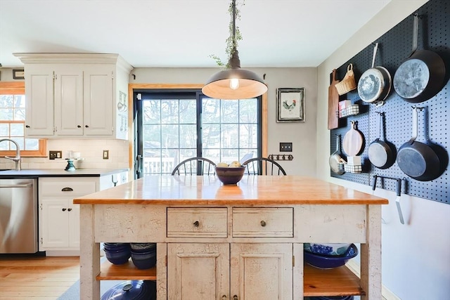 kitchen with light wood-style flooring, decorative light fixtures, backsplash, white cabinets, and dishwasher