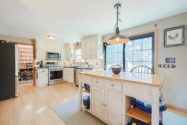 kitchen featuring tasteful backsplash, stainless steel appliances, light wood-style floors, and open shelves