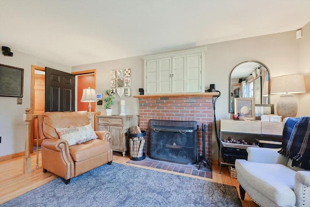 living room featuring a fireplace, baseboards, and wood finished floors