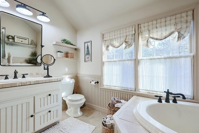 bathroom featuring tile patterned flooring, toilet, vaulted ceiling, wainscoting, and vanity