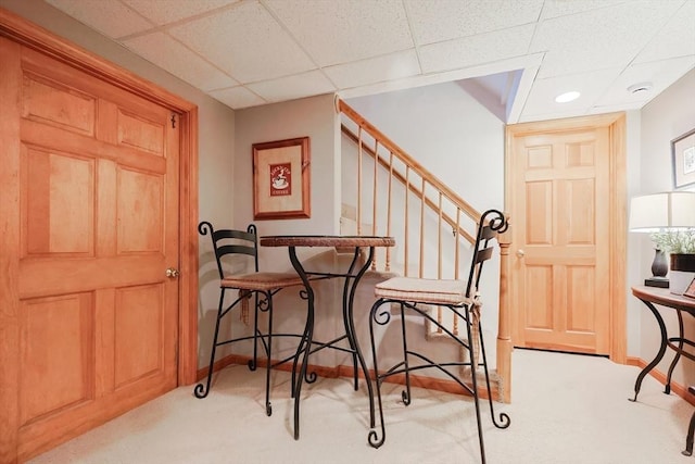 foyer featuring stairway, a paneled ceiling, baseboards, and light carpet