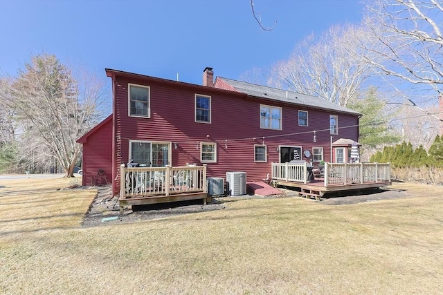 back of property featuring cooling unit, a lawn, a deck, and a chimney