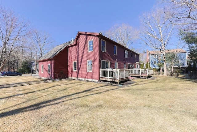 rear view of house featuring a wooden deck and a lawn