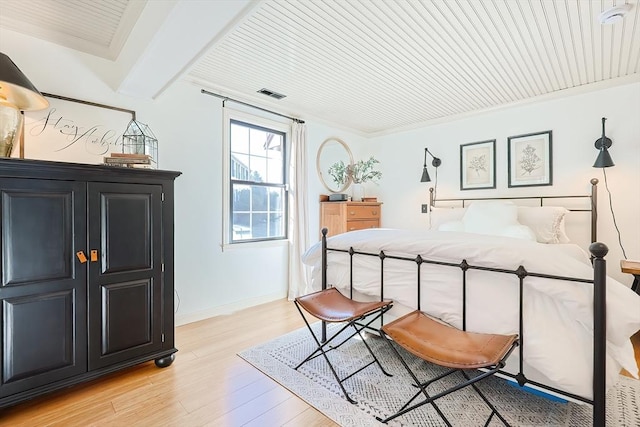 bedroom featuring beamed ceiling, baseboards, visible vents, and light wood-type flooring