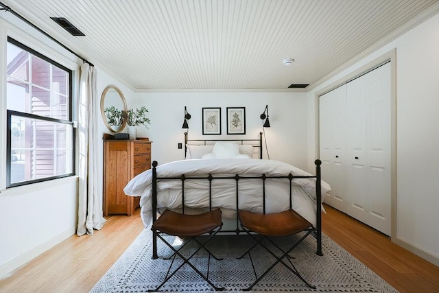 bedroom featuring light wood-type flooring, baseboards, visible vents, and crown molding