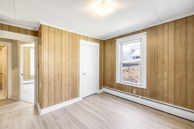 unfurnished bedroom featuring crown molding, a baseboard radiator, a baseboard heating unit, baseboards, and wood finished floors