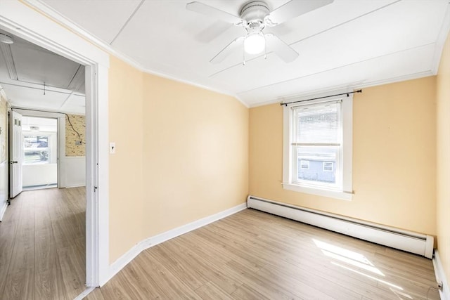 empty room featuring a baseboard heating unit, crown molding, attic access, and plenty of natural light