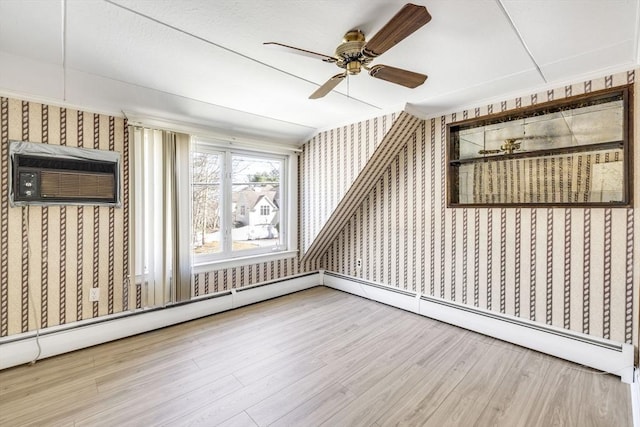 bonus room featuring a wall mounted air conditioner, a ceiling fan, wallpapered walls, and wood finished floors
