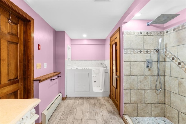 bathroom with hardwood / wood-style flooring, a tile shower, and baseboard heating