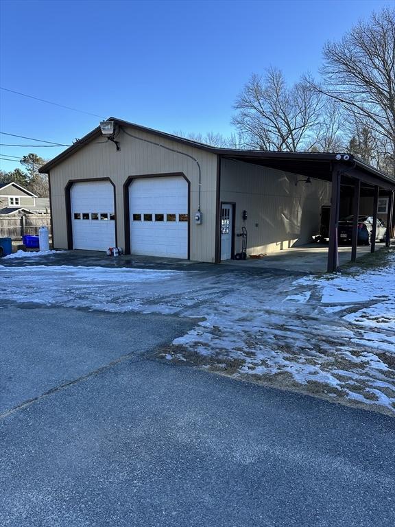 snow covered garage with a carport