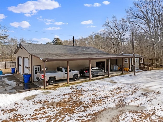 snow covered parking with a carport and a garage