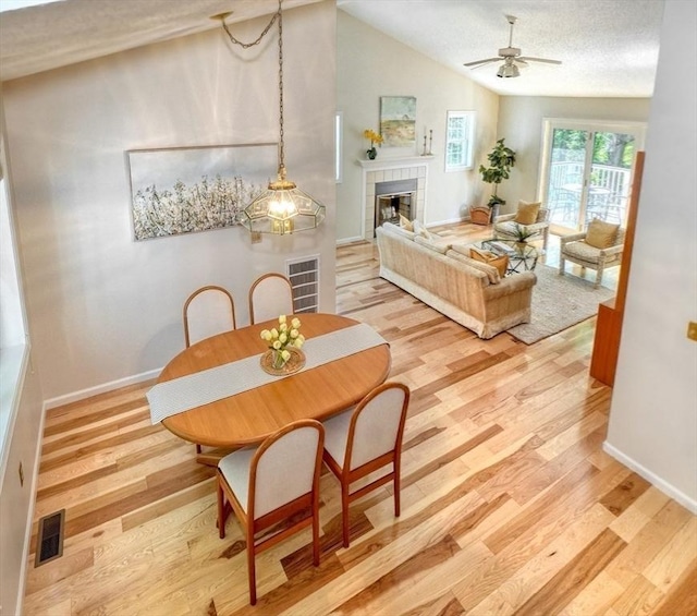 9 Knollwood Ct Unit 9, Burlington, MA 01803 - dining room with light wood-style floors, a tiled fireplace, baseboards, vaulted ceiling, and ceiling fan