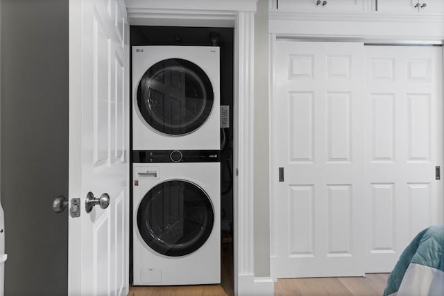 washroom featuring stacked washer and dryer, laundry area, and wood finished floors