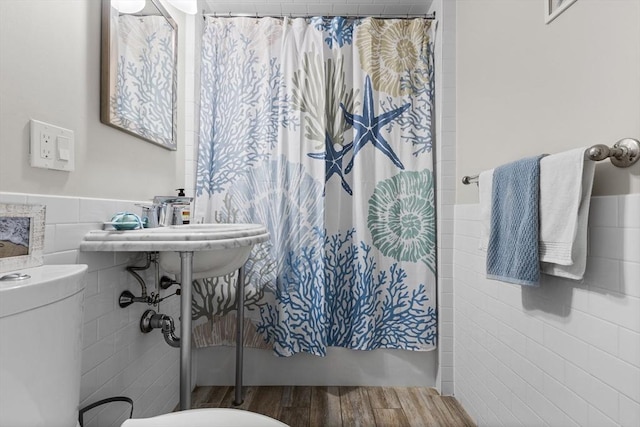 full bath with a wainscoted wall, tile walls, toilet, and wood finished floors