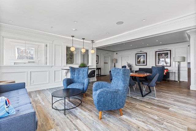 living room featuring ornamental molding, light wood-style flooring, and a decorative wall