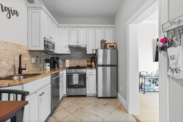 kitchen featuring stainless steel appliances, backsplash, white cabinetry, a sink, and under cabinet range hood