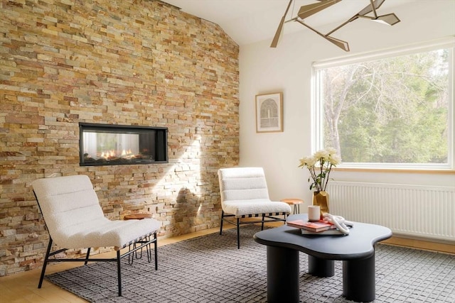 sitting room with vaulted ceiling, a multi sided fireplace, and wood finished floors