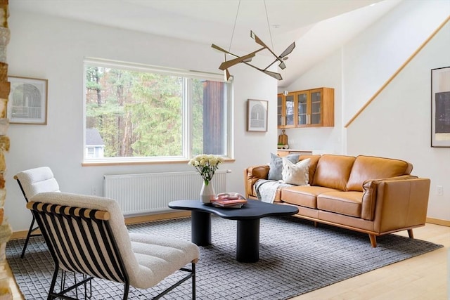 living room with radiator heating unit, light wood-style floors, lofted ceiling, and baseboards