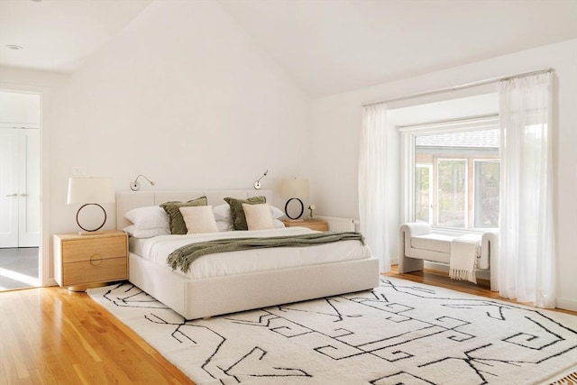 bedroom featuring wood finished floors, lofted ceiling, and baseboards