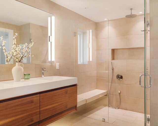 bathroom featuring a stall shower, vanity, tile walls, and tile patterned floors