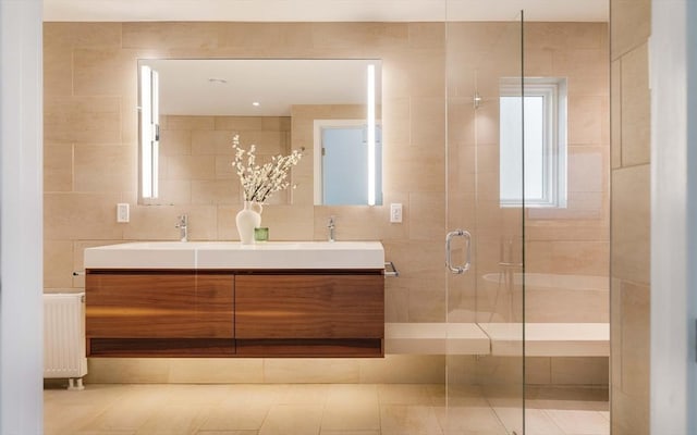 full bath featuring a shower stall, tile walls, double vanity, radiator heating unit, and tile patterned flooring