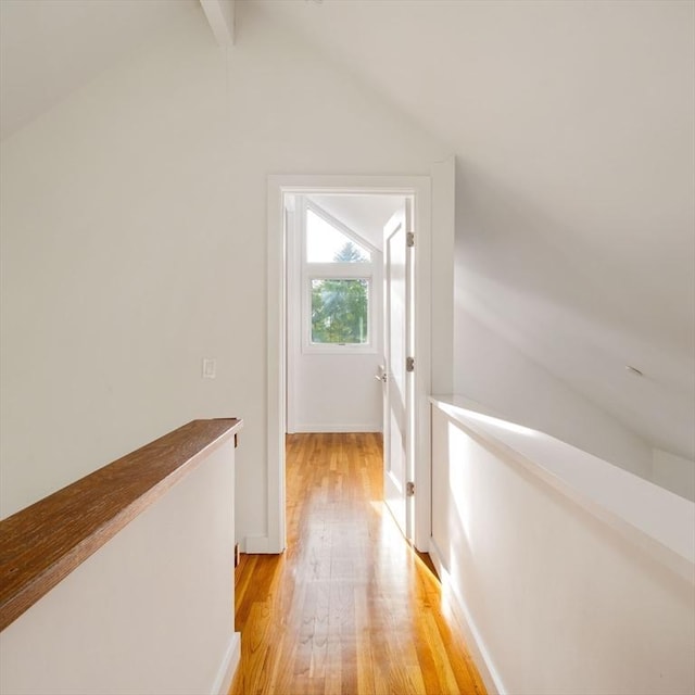 corridor with light wood-style flooring, an upstairs landing, and baseboards