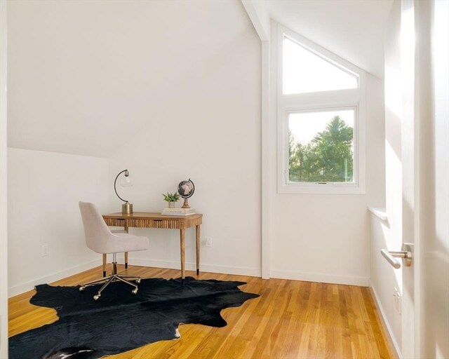 office area with light wood-style flooring, vaulted ceiling, and baseboards
