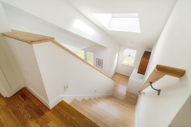 stairs with a skylight, wood finished floors, and baseboards