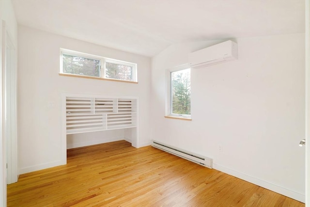 empty room with a baseboard radiator, a wall mounted air conditioner, light wood-style flooring, and baseboards