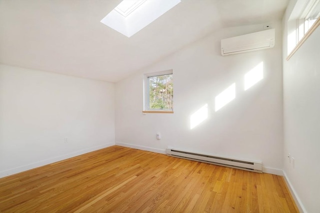 bonus room featuring a baseboard heating unit, a wall unit AC, a skylight, light wood-style floors, and vaulted ceiling