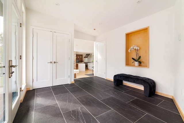 hall with dark marble finish floors and baseboards