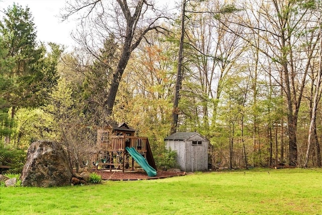 view of playground featuring a lawn, a shed, and an outdoor structure
